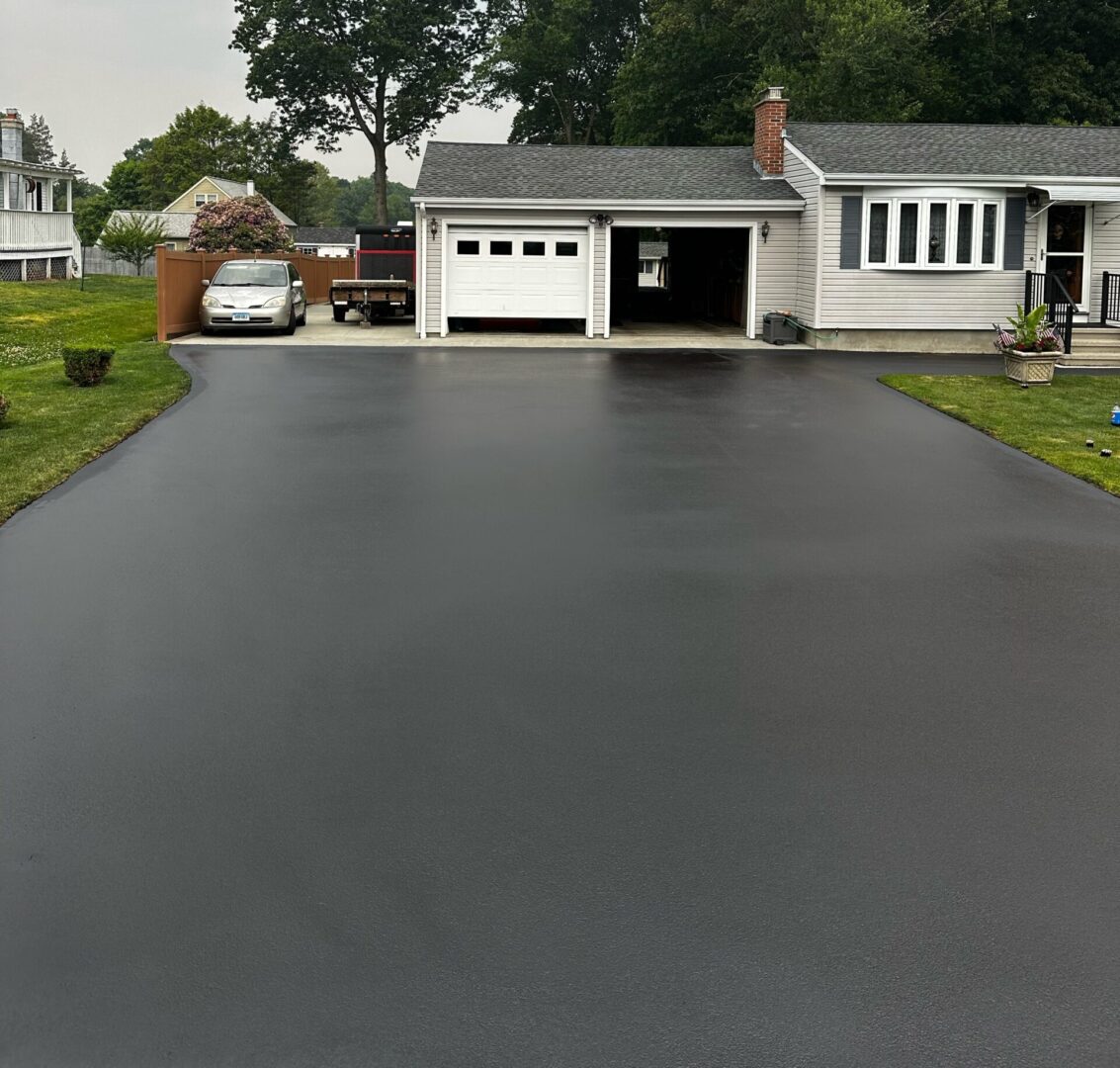 A driveway with black asphalt and grass around it.