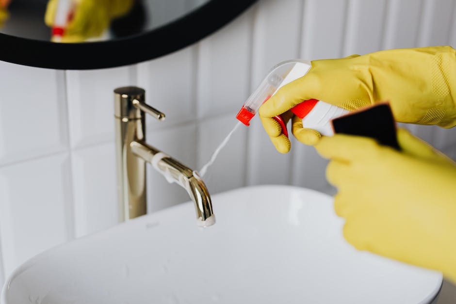 A person in yellow gloves cleaning the faucet.